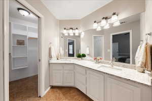 Full bath with connected bathroom, double vanity, a spacious closet, and light tile patterned floors
