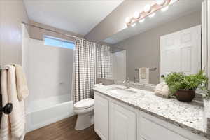 Bathroom featuring shower / bath combo with shower curtain, vanity, and dark wood-style flooring