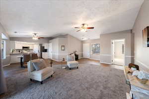 Living room featuring  wood-style floors, a textured ceiling, plenty of natural light, ceiling fan, and lofted ceiling