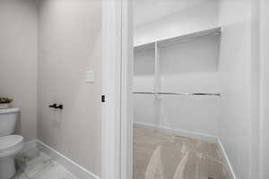 Bathroom featuring light marble finish flooring and a walk in closet