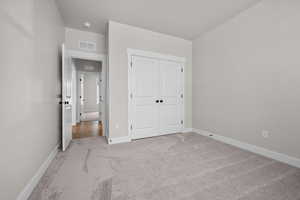 Unfurnished bedroom featuring light carpet and a closet