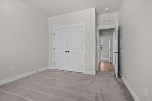 Unfurnished bedroom with light carpet and a closet