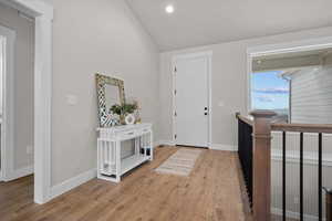 Foyer entrance with lofted ceiling, light wood finished floors, and recessed lighting