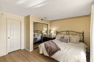 Bedroom featuring light wood-style floors, a closet, and wallpapered walls