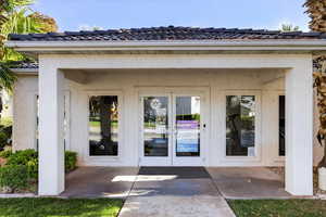 View of exterior entry with a tile roof, french doors, and stucco siding