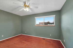 Carpeted empty room with a textured ceiling and ceiling fan