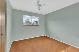 Carpeted spare room with baseboards and a ceiling fan