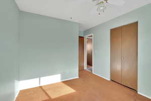 Unfurnished bedroom featuring carpet, a ceiling fan, and a closet