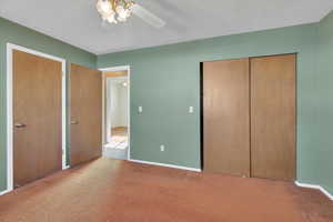 Unfurnished bedroom with two closets, carpet flooring, ceiling fan, and a textured ceiling