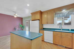 Kitchen with a center island, decorative backsplash, white appliances, light wood-style flooring, and ceiling fan
