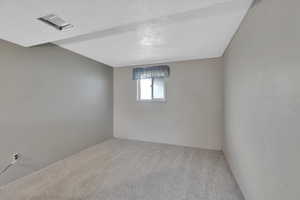Carpeted spare room featuring a textured ceiling