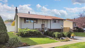 Split foyer home with a chimney, a metal roof, and brick siding