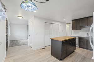 Kitchen featuring wooden counters, light wood finished floors, a kitchen island, dark brown cabinets, and dishwasher
