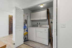 Washroom with washing machine and clothes dryer, cabinet space, and gas water heater