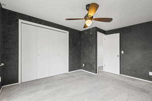 Unfurnished bedroom featuring carpet floors, ceiling fan, and a closet