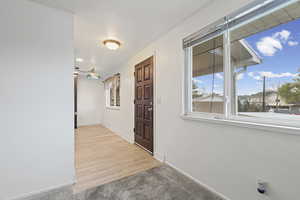 Foyer entrance with baseboards and light colored carpet