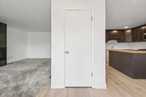 Kitchen featuring butcher block counters, dark brown cabinetry, light wood finished floors, and tasteful backsplash