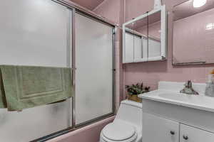 Full bath featuring shower / bath combination with glass door and vanity