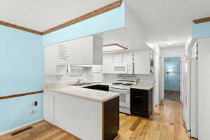 Kitchen featuring white cabinets, light countertops, white appliances, light wood-style flooring, and a textured ceiling