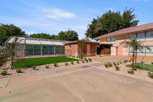 Rear view of house with a lawn, a tiled roof, and a chimney