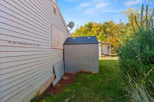 View of side of property with a lawn and a shed