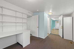 Unfurnished office with baseboards and dark carpet