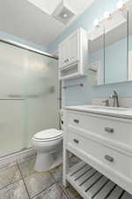 Bathroom featuring vanity, a stall shower, and a textured ceiling