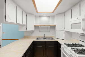 Kitchen featuring white cabinets, white appliances, and light countertops