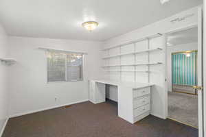 Unfurnished office with dark carpet and baseboards