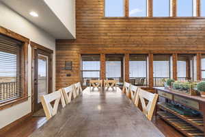 Unfurnished dining area featuring wood walls, dark wood-style flooring, and a high ceiling