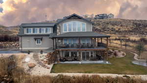 Rear view of property featuring a patio, a shingled roof, a yard, and stairway