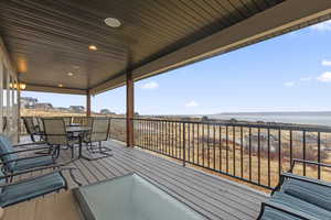 Deck with outdoor dining space and a water view