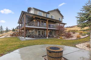 Back of property featuring a patio, stone siding, and a yard