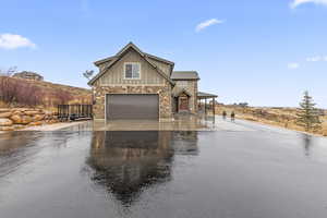 View of front of house featuring asphalt driveway, board and batten siding, stone siding, and a porch