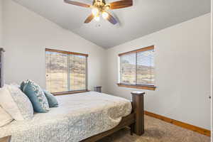 Carpeted bedroom featuring vaulted ceiling and a ceiling fan