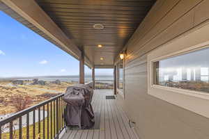 Wooden terrace featuring area for grilling and a water view
