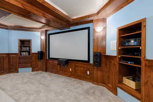 Home theater featuring ornamental molding, built in features, carpet flooring, and a wainscoted wall