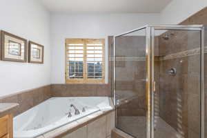 Full bath with a jetted tub, vanity, and a stall shower
