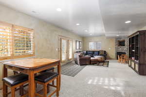 Living area with light carpet, french doors, a stone fireplace, and recessed lighting