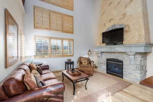 Living area featuring a high ceiling, wood finished floors, and a fireplace