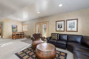 Carpeted living area with recessed lighting and french doors