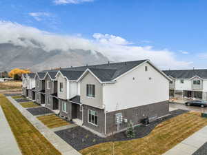 View of property exterior with a residential view, a yard, brick siding, a shingled roof, and board and batten siding