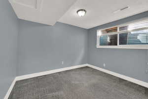 Carpeted spare room with baseboards and a textured ceiling
