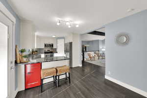 Kitchen with a peninsula, appliances with stainless steel finishes, dark stone countertops, a breakfast bar, and white cabinets