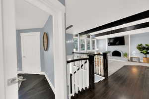 Hall featuring an upstairs landing, dark wood finished floors, and beam ceiling