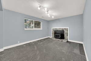 Unfurnished living room featuring a wood stove, carpet, and a textured ceiling