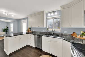 Kitchen with a peninsula, dark stone counters, wood finish floors, and stainless steel appliances