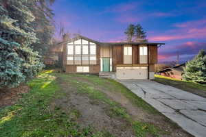 Raised ranch with driveway, a garage, and a chimney