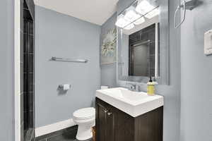 Full bath with vanity, a tile shower, and a textured wall