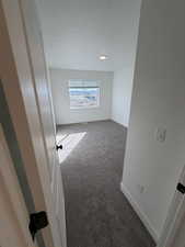 Carpeted empty room featuring baseboards and a textured ceiling
